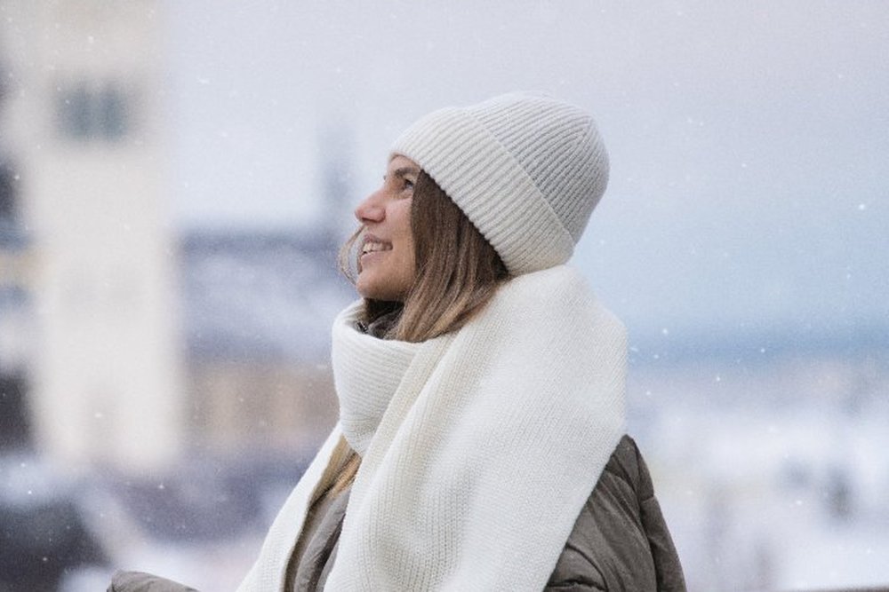 Žena v bílé pletené vlněné čepici na zasněžené terase